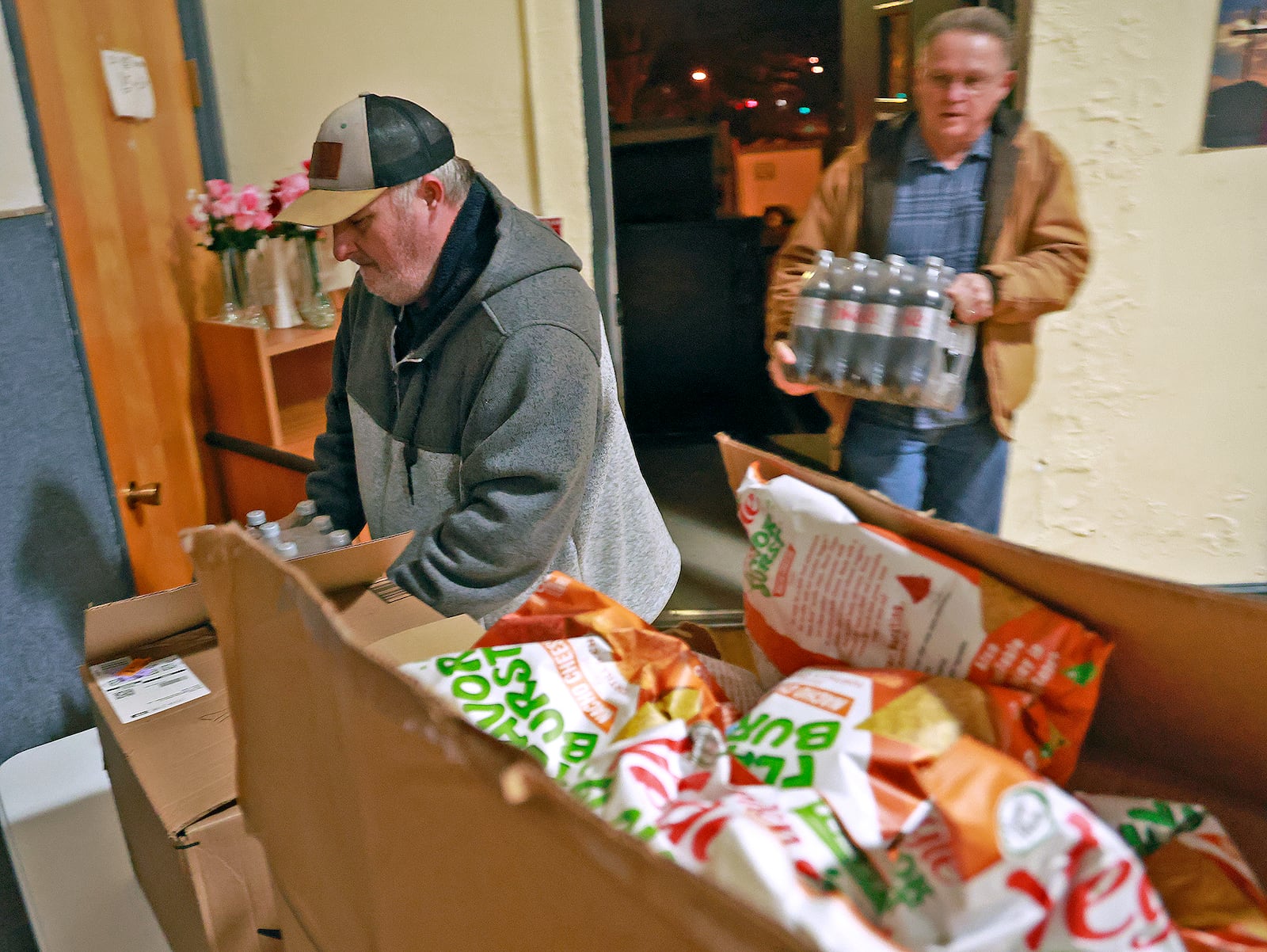 Volunteers drop off cases of food and drinks Tuesday evening at the warming shelter in the Victory Faith Center gymnasium. The shelter was organized by Kenneth "Barron" Seelig with help from community volunteers as temperatures dropped below freezing outside. The shelter, which also offers a hot meal, opened for the first time on Monday. BILL LACKEY/STAFF