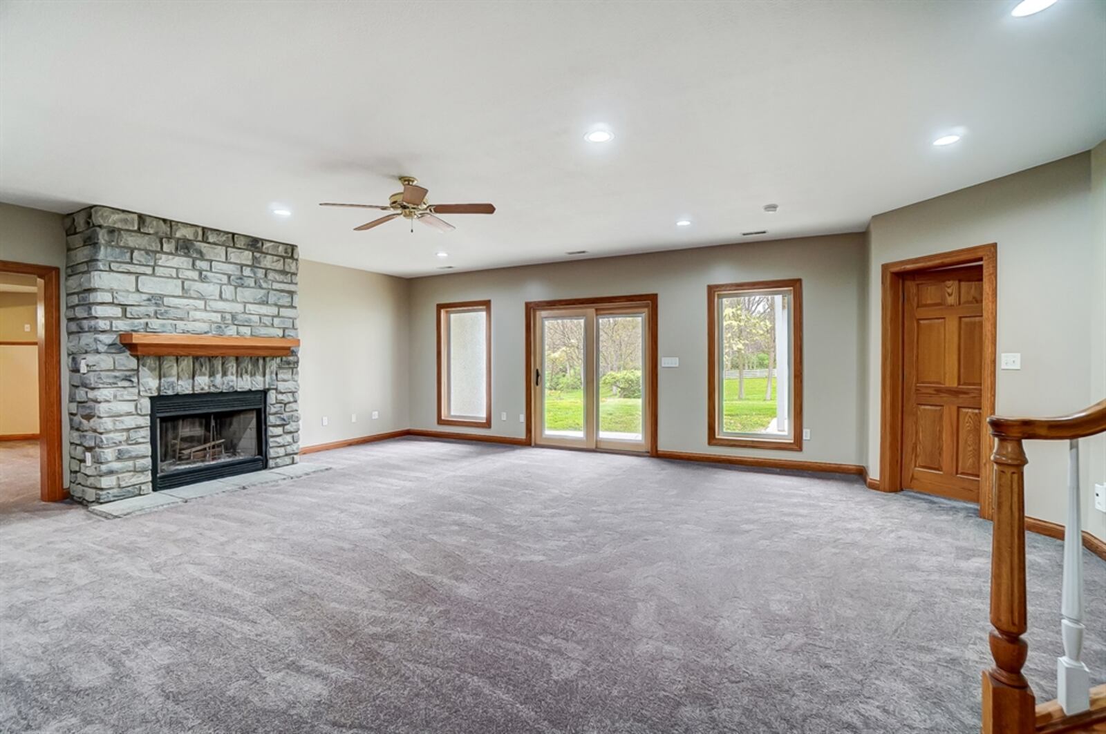 A stone fireplace has a wood-burning insert, raised stone hearth and rough-cut wood beam mantel. 