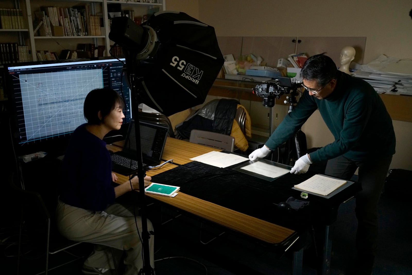 Ai Saotome, left, and Shinji Teruya digitize old manuscripts at Saotome's father Honorary Director Katsumoto Saotome at the Center of the Tokyo Raids and War Damage, on Feb. 4, 2025, in Tokyo. (AP Photo/Eugene Hoshiko)