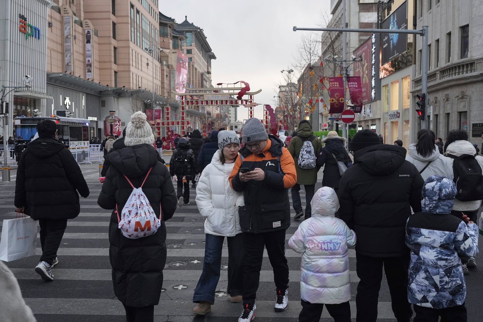 People cross a road at a shopping area in Beijing on Tuesday, Feb. 4, 2025. (AP Photo/Aaron Favila)