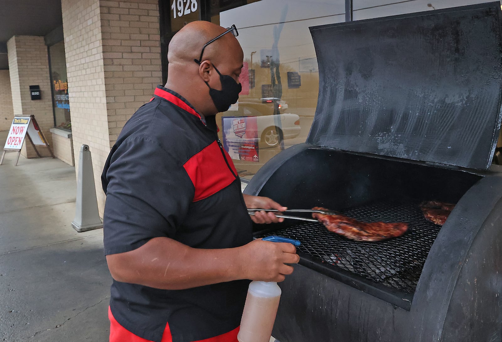 Troy Wheat at the smoker in front of his restaurant, All Seasons, Wednesday. BILL LACKEY/STAFF