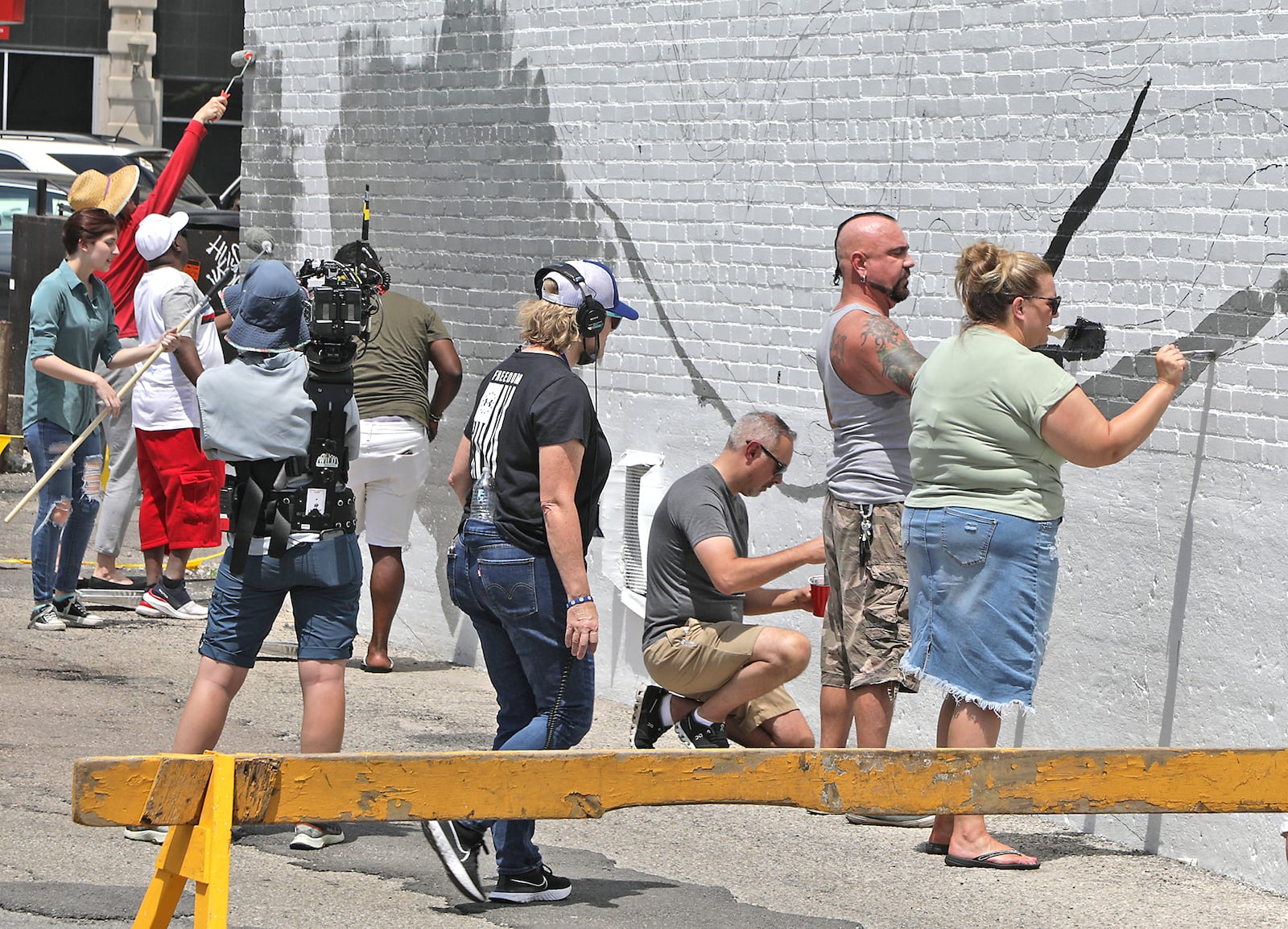 A television production crew films people working on the new mural on the back wall of The State theater Wednesday, June 1, 2022. BILL LACKEY/STAFF