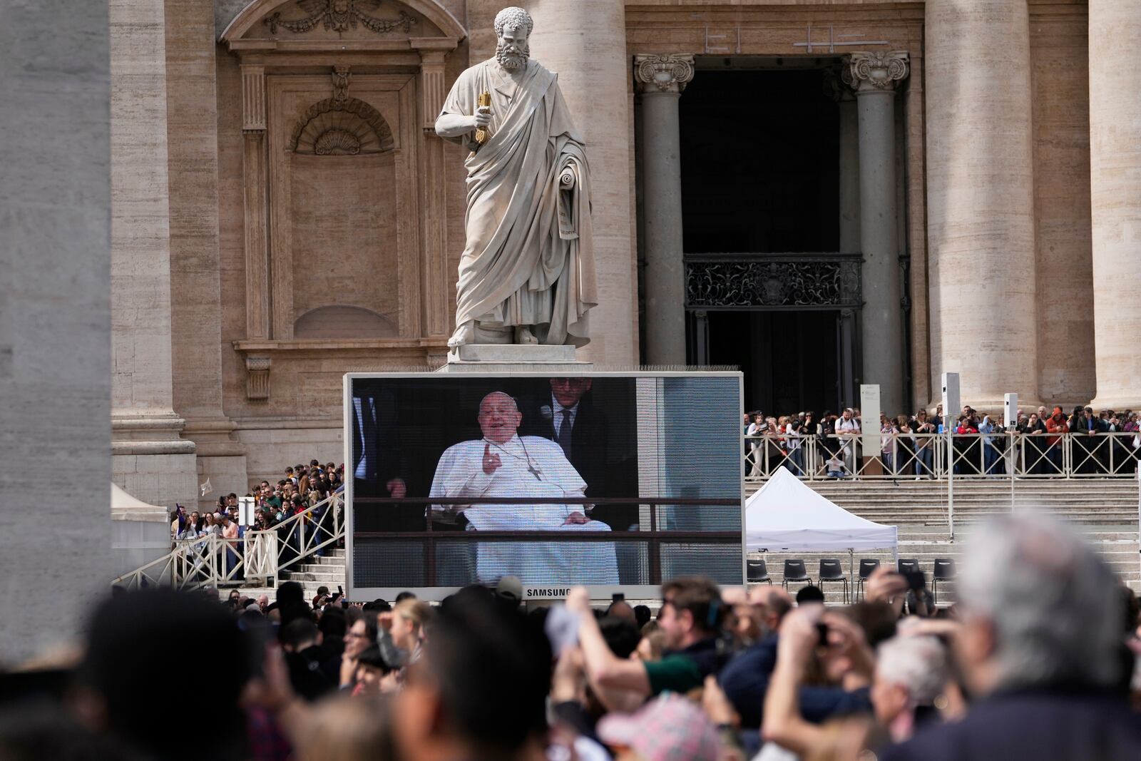 Faithfuls and pilgrims gather in St. Peter's Square at The Vatican to follow on giant screens a live broadcast from Rome's Agostino Gemelli Polyclinic, Sunday, March 23, 2025, where Pope Francis made his first public appearance since he was hospitalized on Feb. 14 with bilateral pneumonia. (AP Photo/Gregorio Borgia)