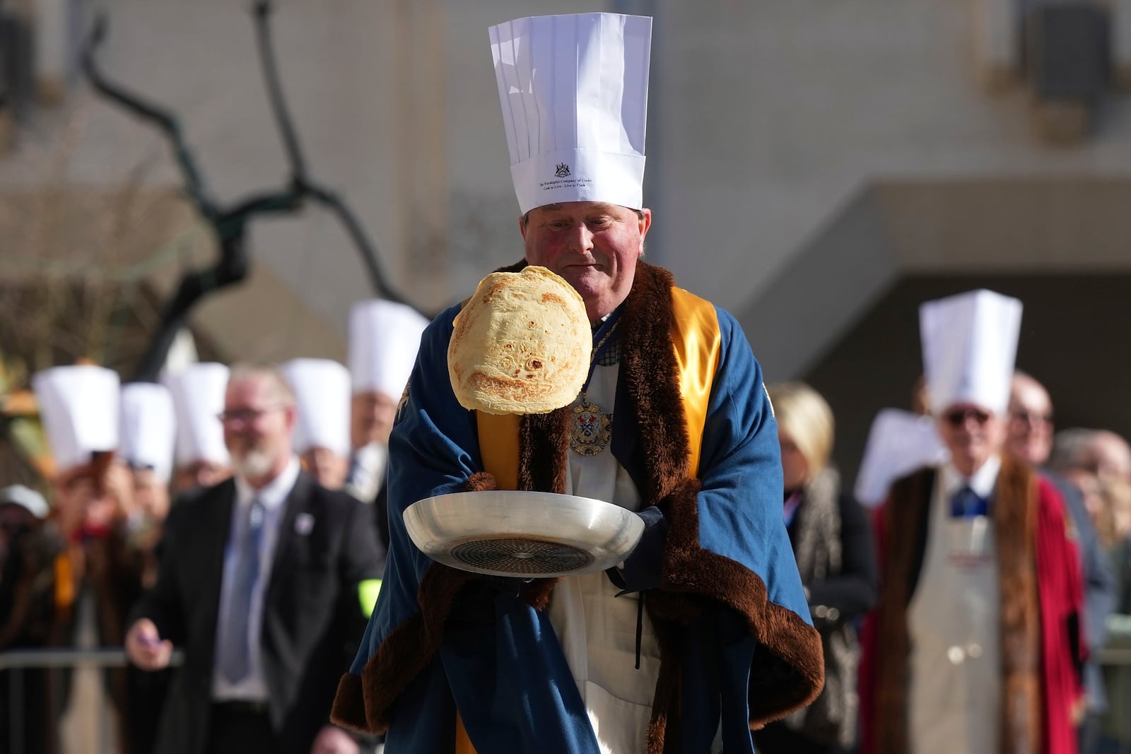 A competitor flips a pancake during a traditional pancake race by livery companies at the Guildhall in London, Tuesday, March 4, 2025. (AP Photo/Frank Augstein)