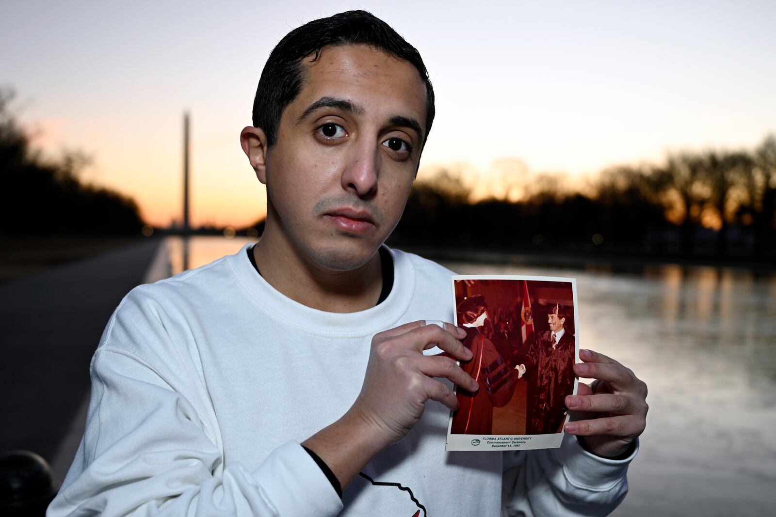 Ibrahim Almadi holds a photo of his father Saad Almadi graduating from college in 1984, in Washington Monday, Dec. 23, 2024. Saad Almadi, a dual U.S.-Saudi citizen was jailed for social media posts critical of the kingdom's crown prince. He was released from a Saudi prison in March 2023 and banned from returning to his home in south Florida. (AP Photo/John McDonnell)