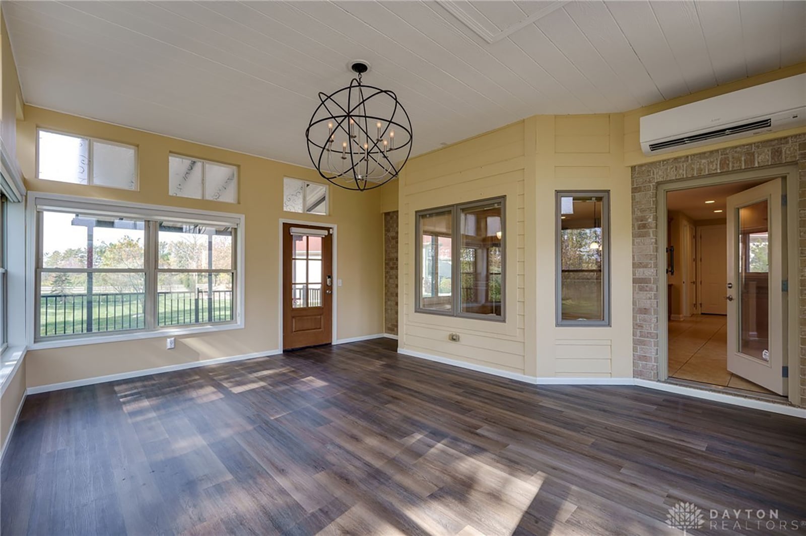 The sun room is off the kitchen and has a a decorative ceiling light and an exterior door leading to the rear covered deck.