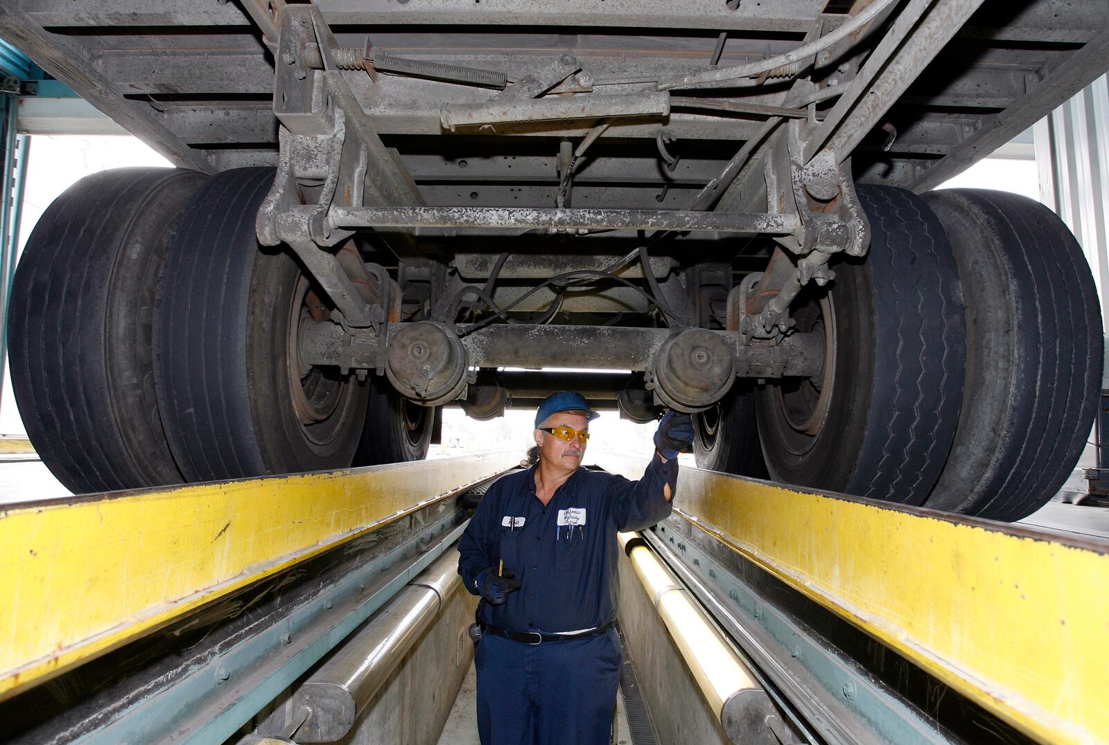 FILE - California Highway Patrol commercial vehicle inspector Ruben Montanez inspects the undercarriage of a truck entering the U.S. from Mexico at the CHP's Otay Mesa Inspection Station Thursday, Sept. 6, 2007, in San Diego. (AP Photo/Denis Poroy)