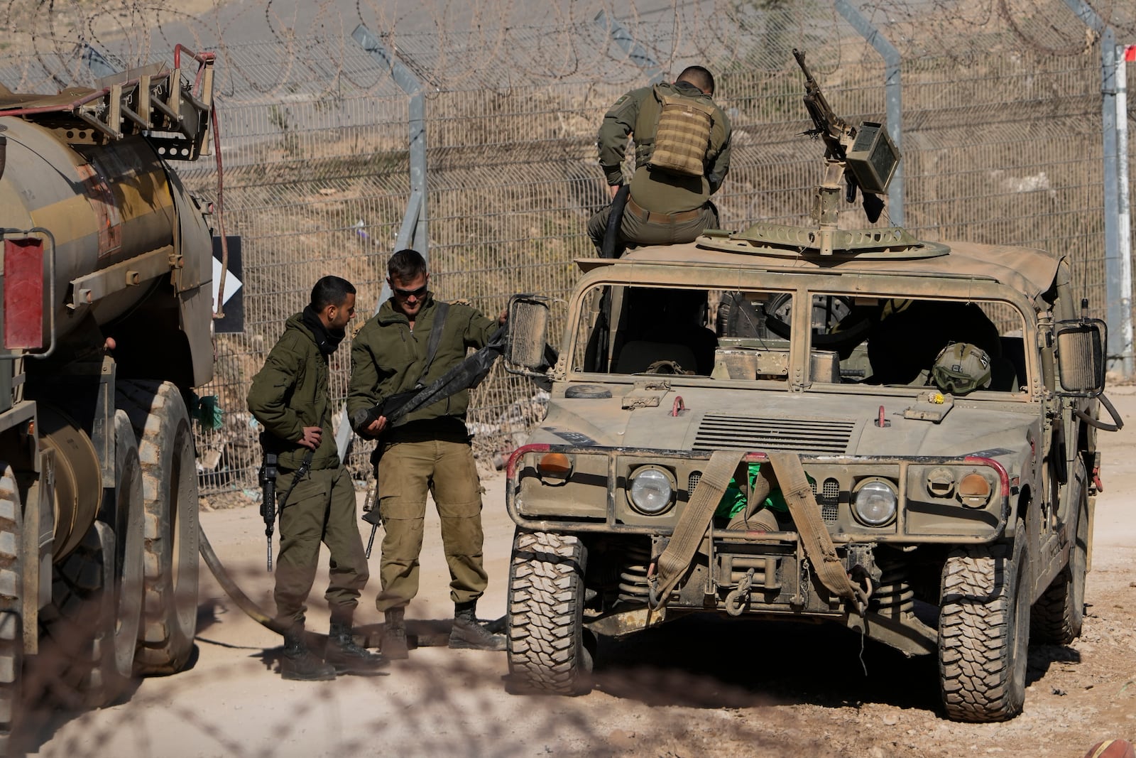 Israeli soldiers stand next to armoured vehicles after crossing the security fence, near the so-called Alpha Line that separates the Israeli-controlled Golan Heights from Syria, in the town of Majdal Shams, Tuesday, Dec. 17, 2024. (AP Photo/Matias Delacroix)