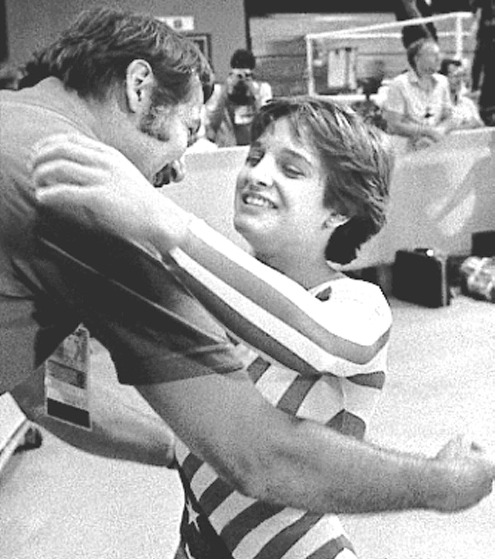 FILE - Mary Lou Retton of the USA is hugged by her coach, Bela Karolyi, following her perfect performance in the floor exercise in Olympic individual all-around finals, Aug. 3, 1984, in Los Angeles. (AP Photo/Sadayuki Mikami, File)