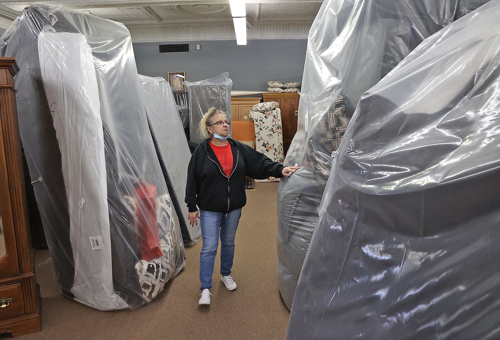 Sue Call, owner of Sue's Furniture in Springfield, walks through the new sofas, wrapped in plastic, Tuesday. Sue has had to turn part of her showroom into storage. Sue says she buys furniture when it becomes available because she doesn't know when she might get the chance again. BILL LACKEY/STAFF