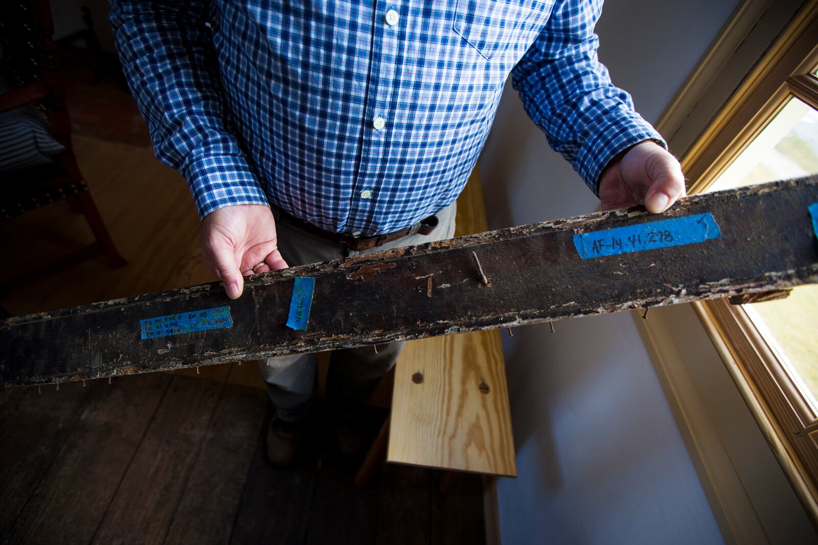 Matthew Webster shows an original rail from the classroom of the Williamsburg Bray School on Wednesday, Oct 30, 2024 in Williamsburg, Va. (AP Photo/John C. Clark)