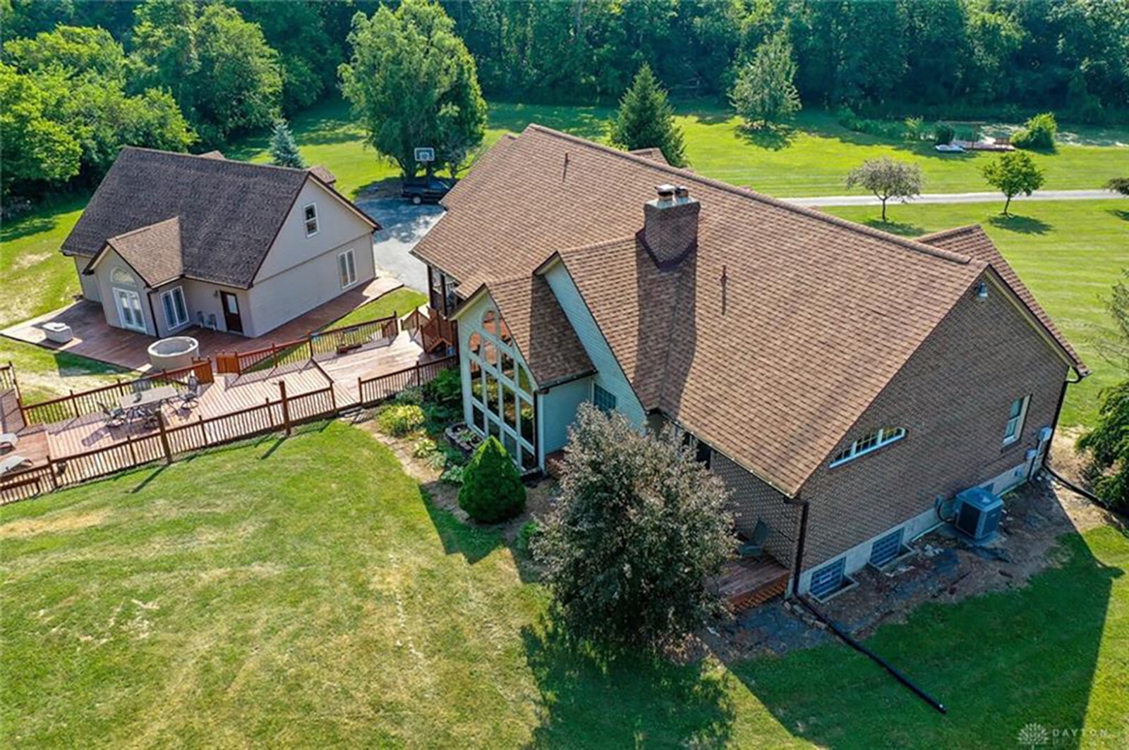 Connected to the back of the home is an oversized wood deck with railing. The deck is raised and has multiple wood stairs, with one staircase leading down to a ground level wood deck behind the detached garage, which has a loft. CONTRIBUTED PHOTO