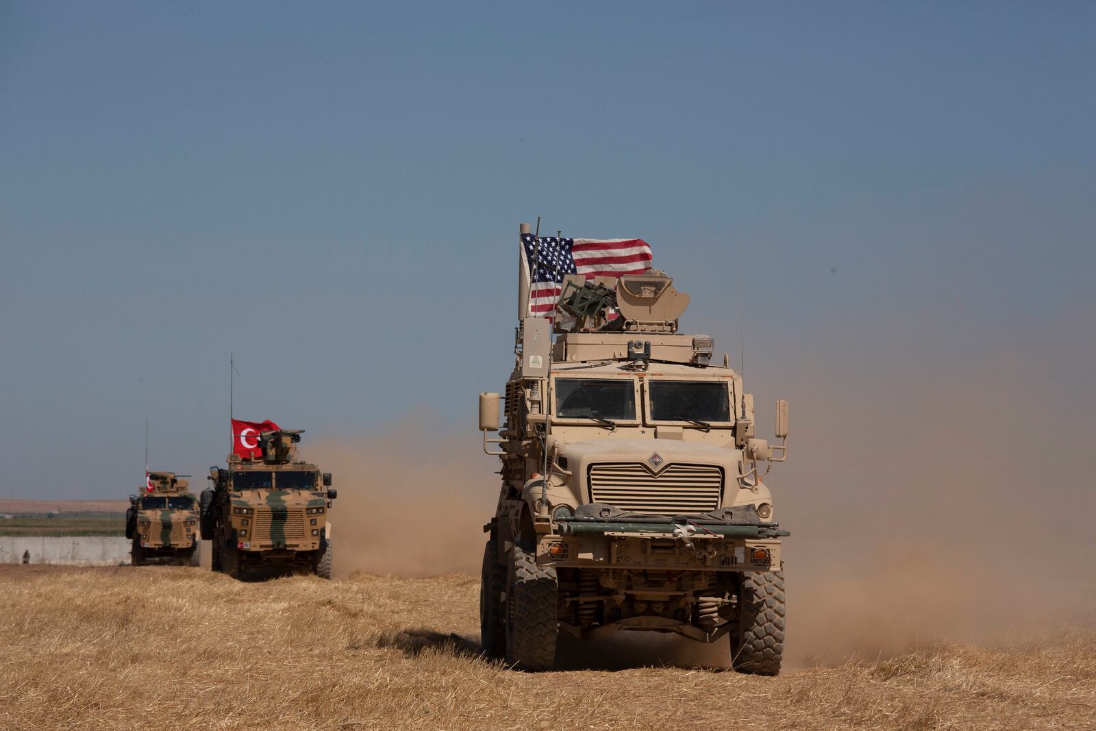 FILE - Turkish and American armored vehicles conduct the first joint patrol in the so-called "safe zone" on the Syrian side of the border with Turkey near Tal Abyad, Syria, Sept. 8, 2019. (AP Photo/Maya Alleruzzo, File)