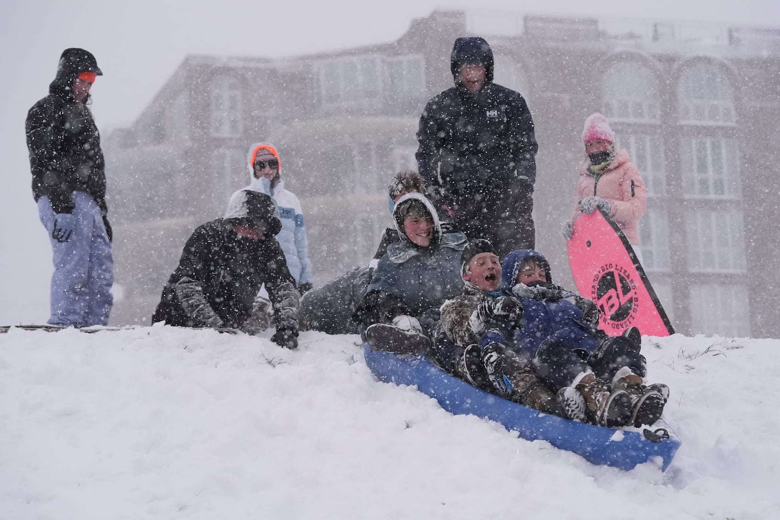 People sled on the backside of the Mississippi River levee as snow falls in New Orleans, Tuesday, Jan. 21, 2025. (AP Photo/Gerald Herbert)