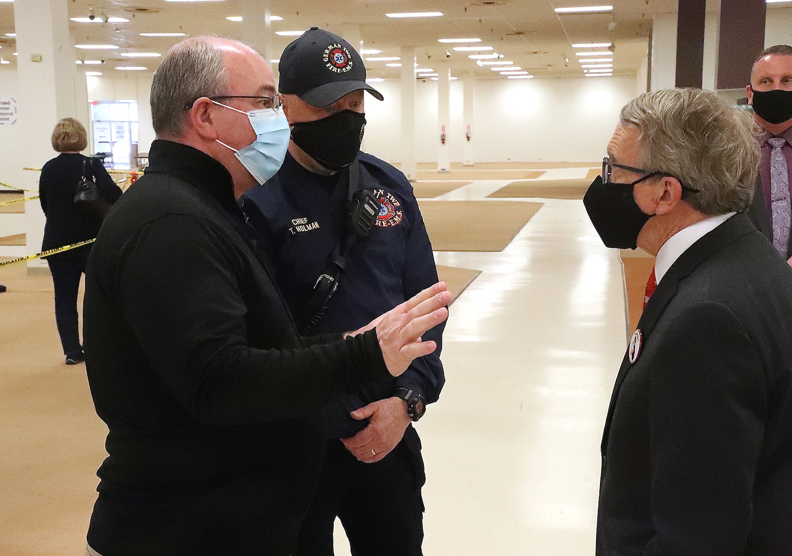 German Township Fire Chief Tim Holman and Clark County Health Commissioner Charles Patterson talk to Governor Mike DeWine during the governor's 2021 stop at the COVID vaccine distribution center in Clark County. BILL LACKEY/STAFF