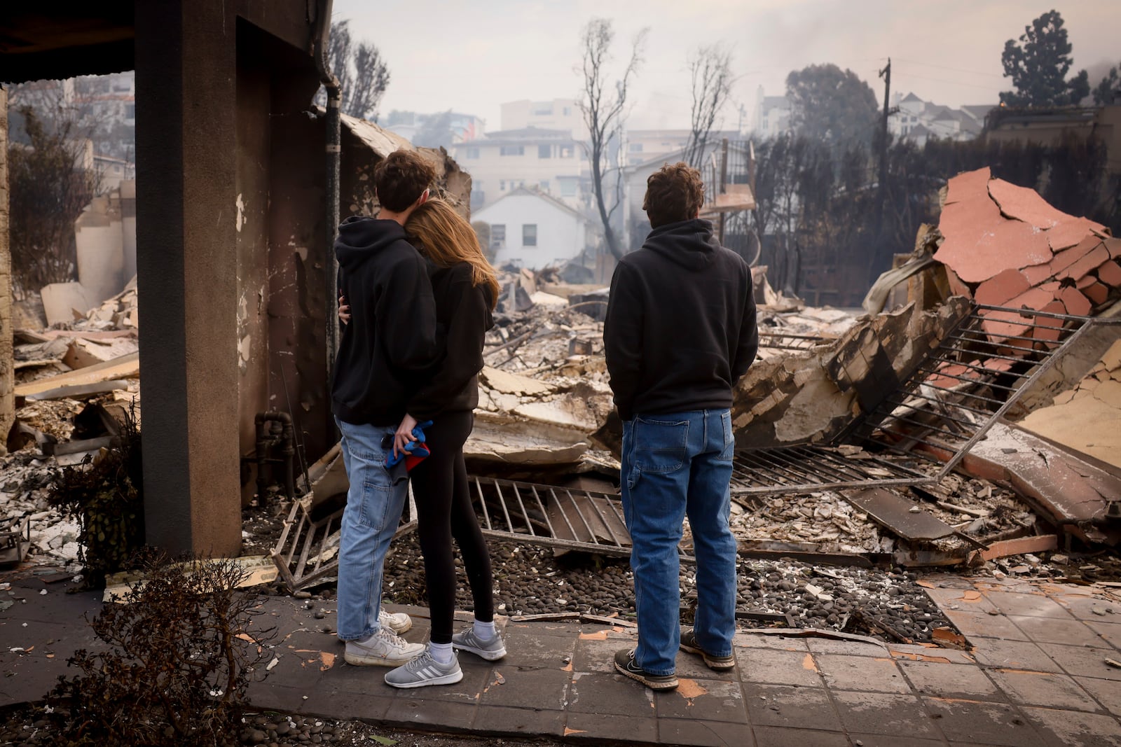 Residents embrace in front of a fire-ravaged property after the Palisades Fire swept through in the Pacific Palisades neighborhood of Los Angeles, Wednesday, Jan. 8, 2025. (AP Photo/Etienne Laurent)