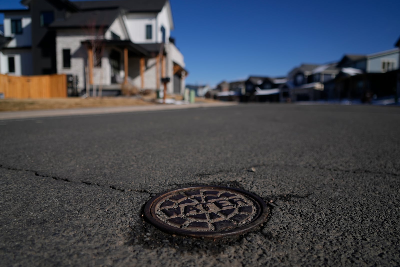 A cover with the word water is visible on a street that is used to access a water main line Thursday, Feb. 13, 2025, in Louisville, Colo.(AP Photo/Brittany Peterson)