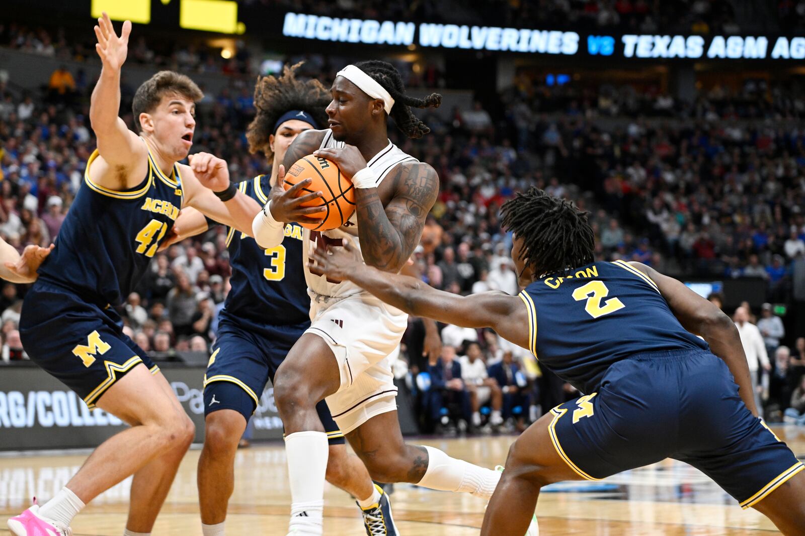 Texas A&M guard Manny Obaseki, front center, drives to the basket as, from left to right, Michigan forward Will Tschetter, guard Tre Donaldson and guard L.J. Cason defend during the first half in the second round of the NCAA college basketball tournament Saturday, March 22, 2025, in Denver. (AP Photo/John Leyba)