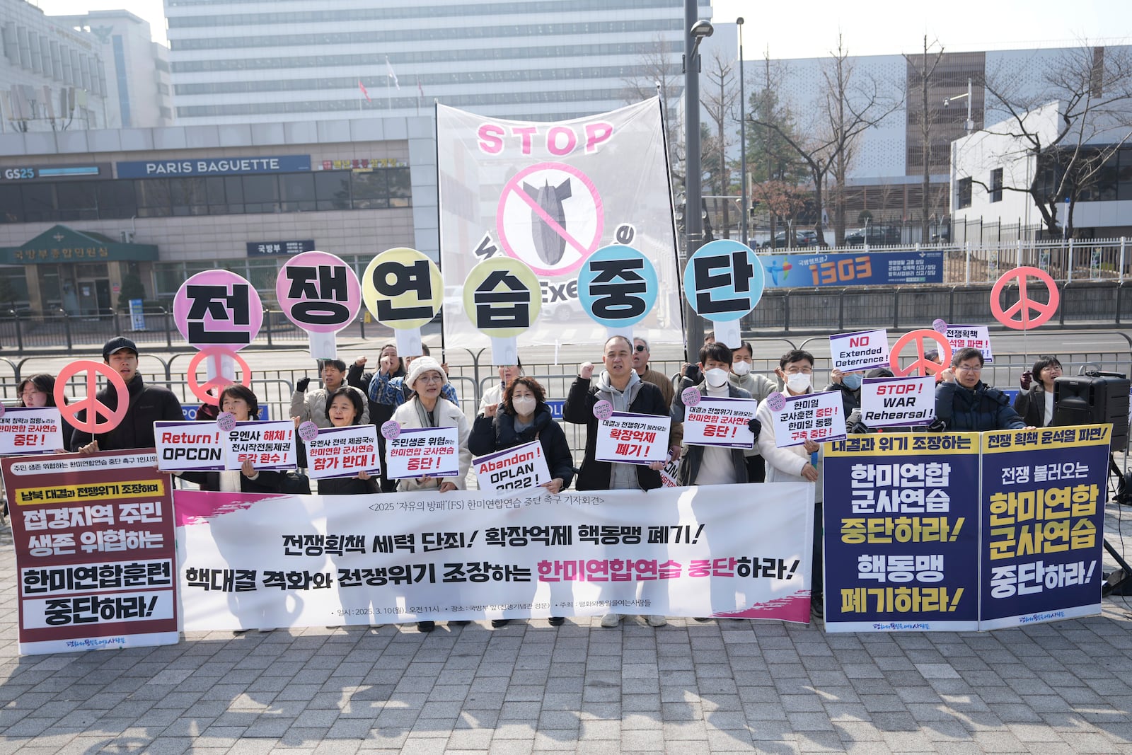 Protesters shout slogans during a press conference demanding to stop the upcoming Freedom Shield military exercise between the U.S. and South Korea, near the Defense Ministry in Seoul, South Korea, Monday, March 10, 2025. The letters read "Stop, War exercise." (AP Photo/Lee Jin-man)