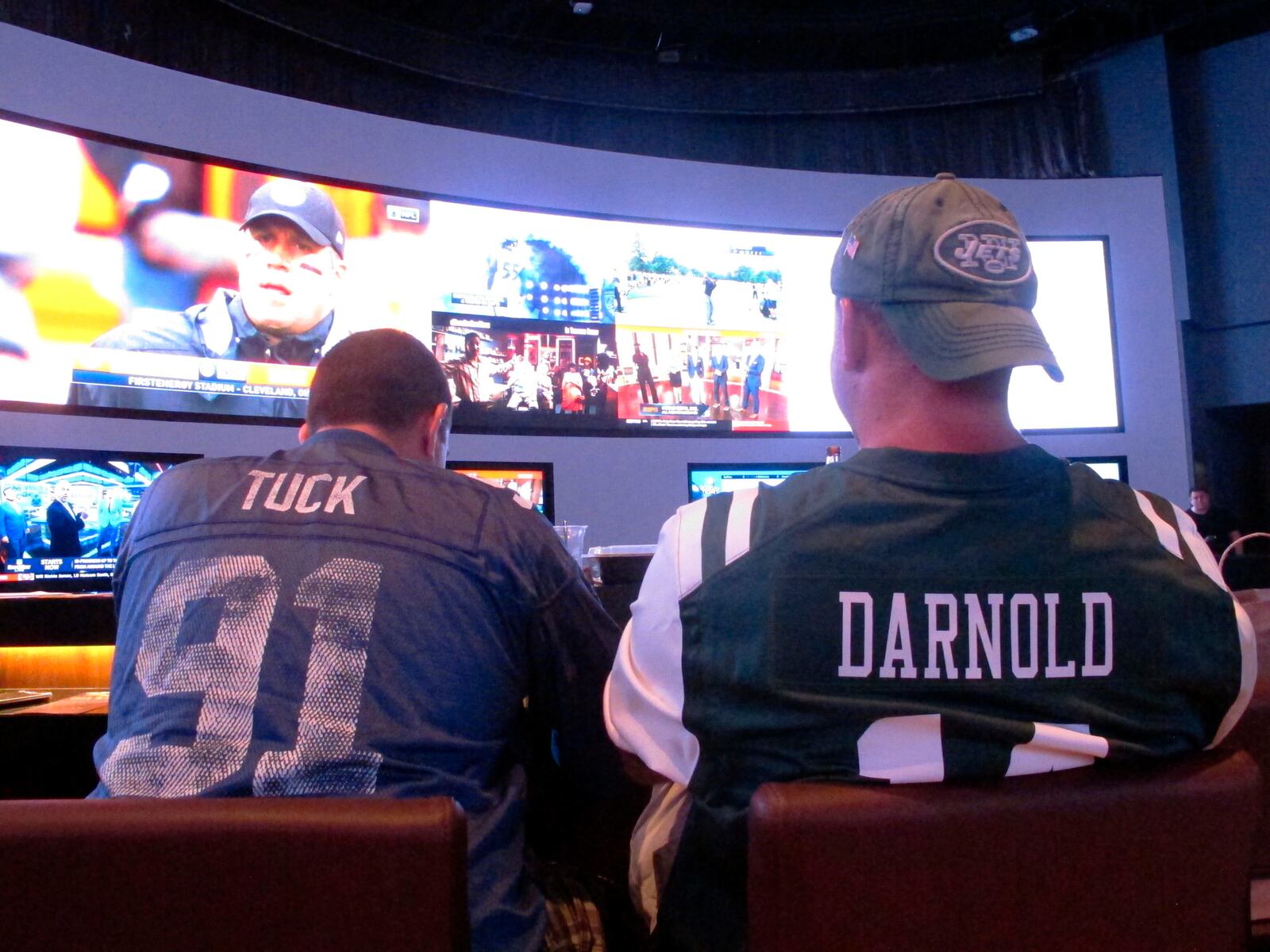 This Sept. 9, 2018 photo shows fans of the New York Giants and Jets watching a football game after placing bets in the sports betting lounge at the Ocean Casino Resort in Atlantic City, N.J. The coronavirus outbreak has added new wrinkles for bettors this year, but even so, the nation's sports books expect a record year of bets on football in 2020 from an antsy public that has been cooped up for months amid the pandemic. (AP Photo/Wayne Parry)