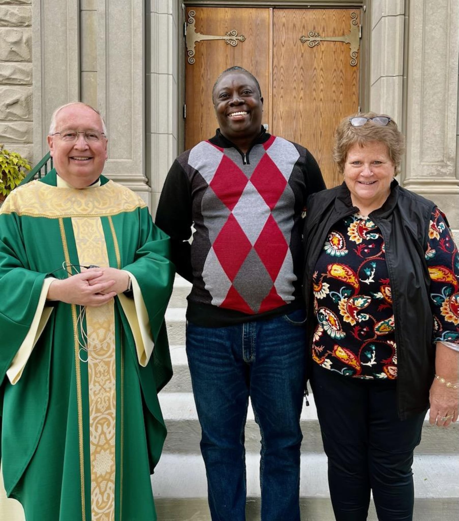 Rev. John MacQuarrie, Patrick Joseph and Casey Rollins stand in front of St. Bernard Catholic Church in Springfield. MacQuarrie is pastor of Springfield's Catholic churches, Joseph is an immigrant from Haiti living in Springfield who volunteers with St. Vincent de Paul in Springfield and Rollins is board president and executive director at St. Vincent de Paul.