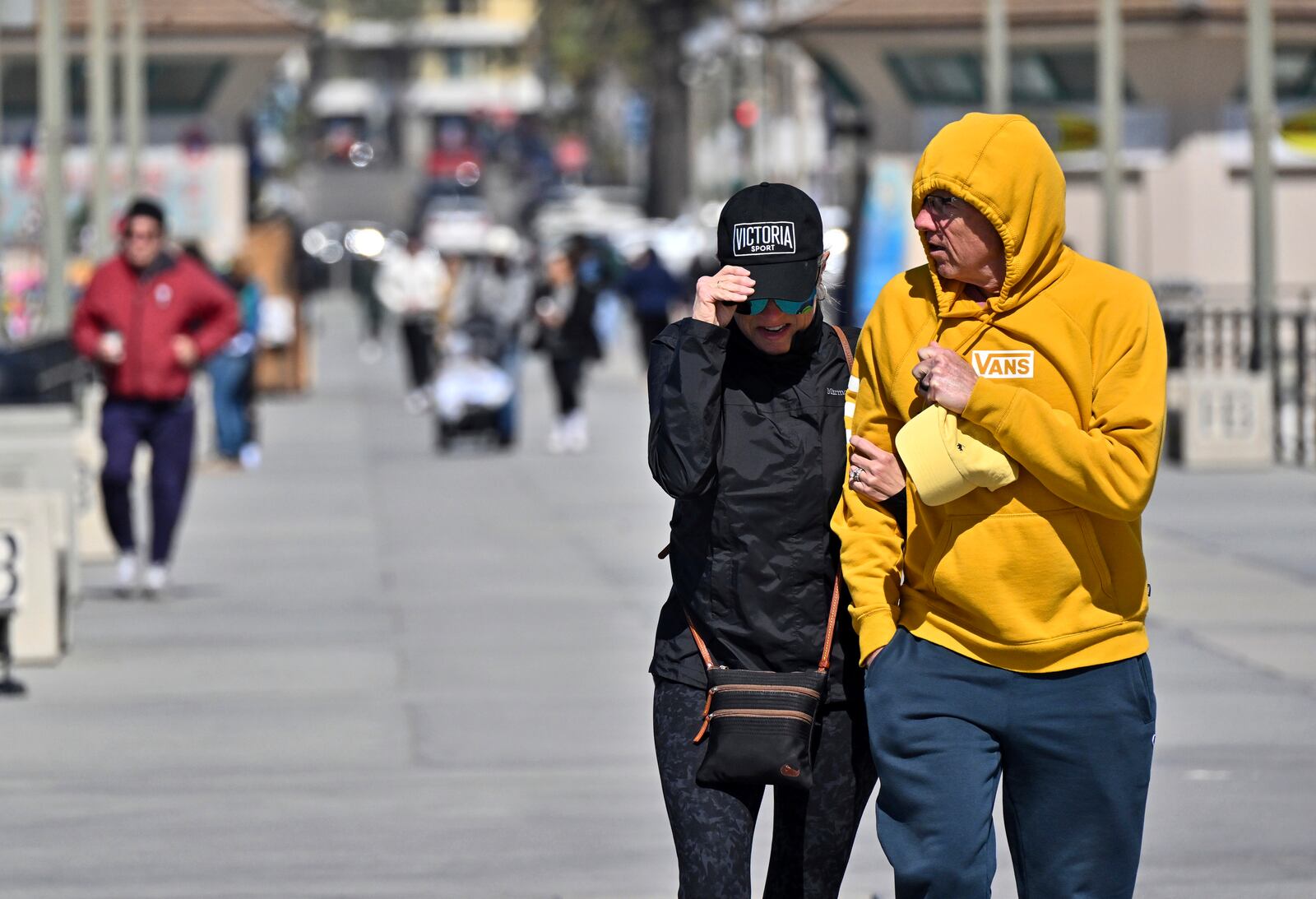 Melissa Jones and her husband, Jeff Jones, visiting from Lincoln, Neb., walk through the wind on the pier in Huntington Beach, Calif., Thursday, March 13, 2025, after strong storms moved through the region overnight. (Jeff Gritchen/The Orange County Register via AP)