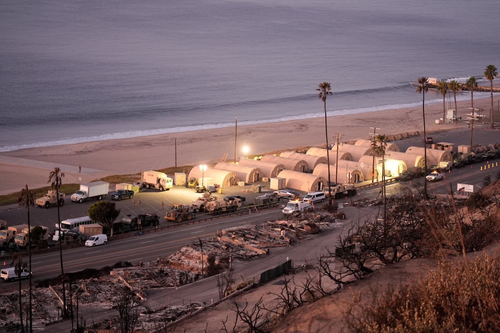 Members of the National Guard set up a beachfront camp across homes destroyed by the Palisades Fire in the Pacific Palisades neighborhood of Los Angeles, Thursday, Jan. 16, 2025. (AP Photo/Damian Dovarganes)