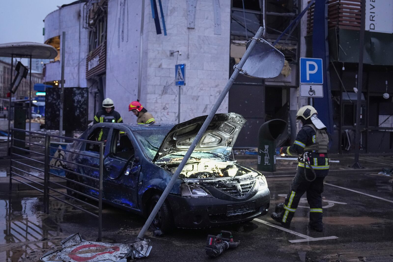 A destroyed car is seen as firefighters work on the site of a damaged building after a Russian missile attack in Kyiv, Ukraine, Saturday, Jan. 18, 2025. (AP Photo/Efrem Lukatsky)