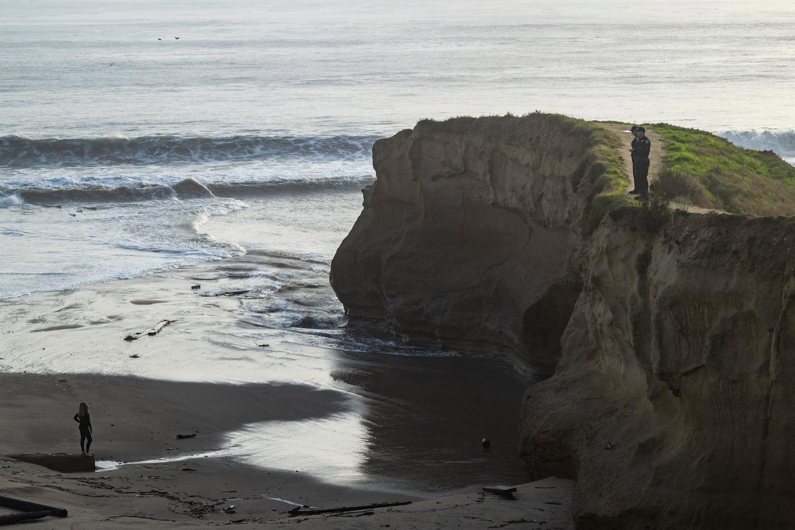 Police officers, right, look for building remnants on Seabright State Beach during high surf in Santa Cruz, Calif., Monday, Dec. 23, 2024. (AP Photo/Nic Coury)