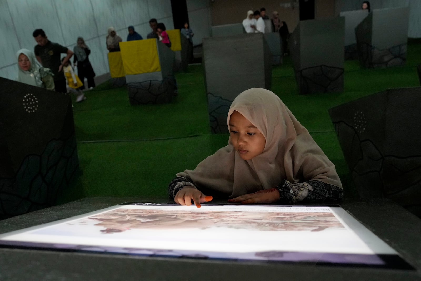 A young girl looks at a photo displayed at the Tsunami Museum in Banda Aceh, Indonesia, Saturday, Dec 14, 2024. (AP Photo/Achmad Ibrahim)