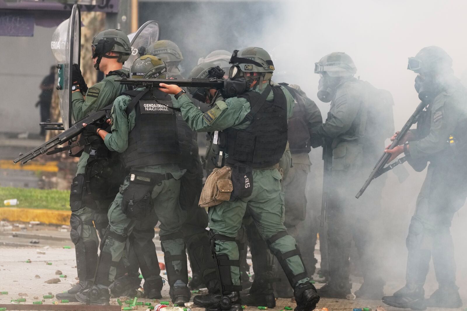 Police hold up their guns during clashes against soccer fans who joined retirees protesting for higher pensions and against austerity measures implemented by Javier Milei's government in Buenos Aires, Argentina, Wednesday, March 12, 2025. (AP Photo/Natacha Pisarenko)