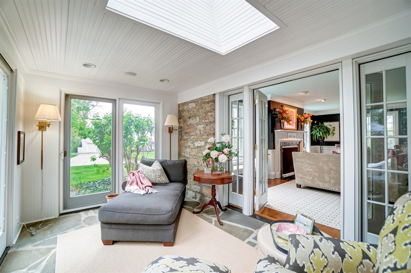 French doors open out to an enclosed porch with a stone wall and bead-board accents. 