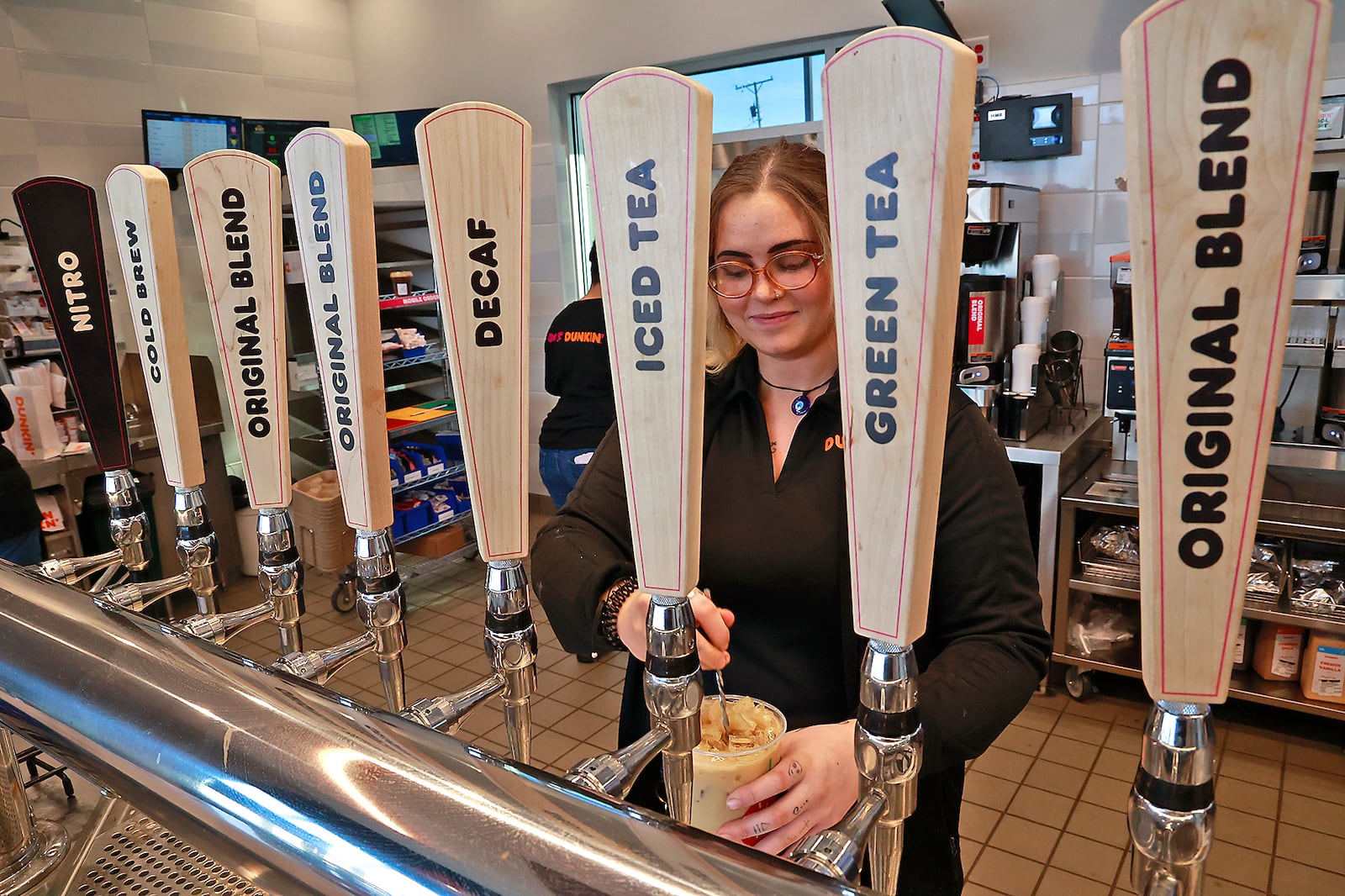 Tayler Bailey, general manager of the new Duncan' in Urbana, is seen through the coffee taps as she makes a coffee drink in the restaurant on East Route 36 Monday, Dec. 5, 2022. BILL LACKEY/STAFF