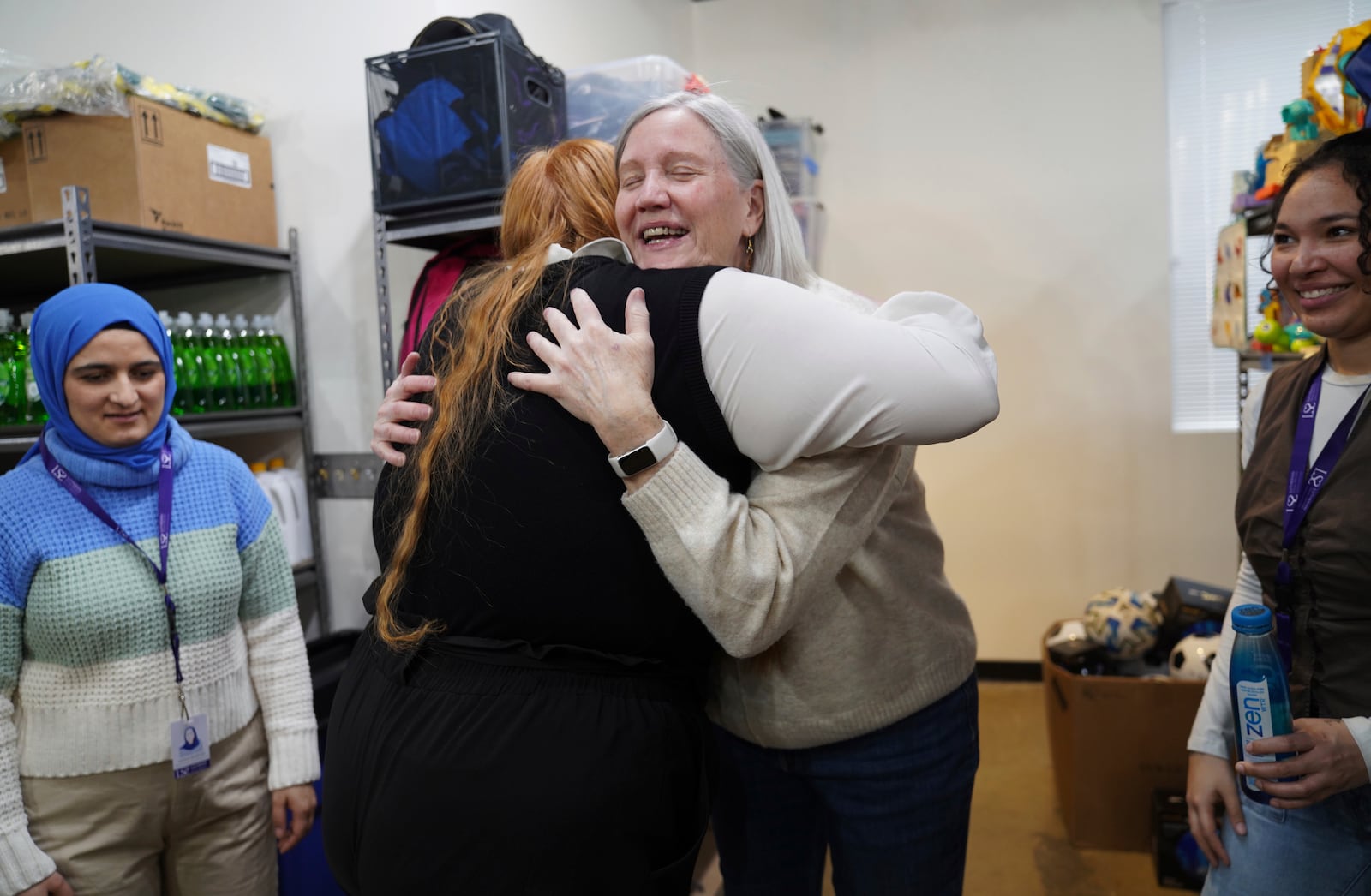 Asma Baburi, left, Alyssa Clifford, Beth Hickey, a volunteer, and Madi Davis, share a conversation while at the Lutheran Social Services National Capital Area Resource Center in Alexandria, Va., Thursday, March 6, 2025. (AP Photo/Jessie Wardarski)