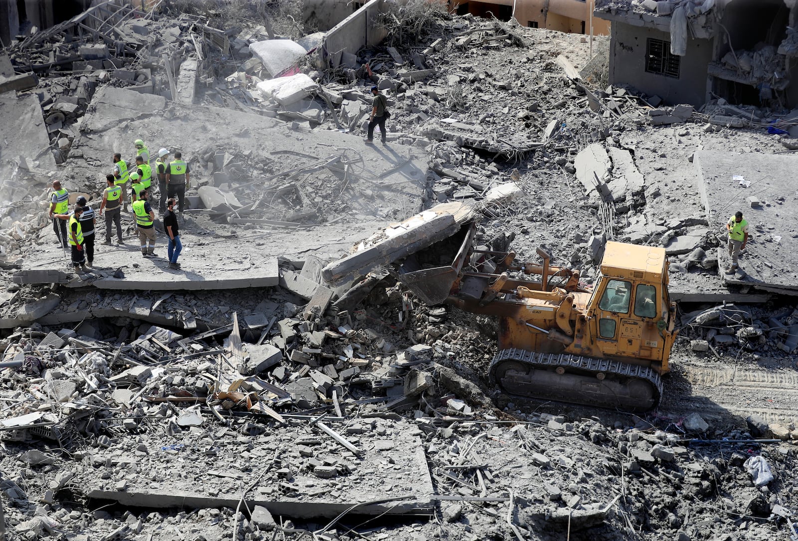 Rescue workers use a bulldozer to remove rubble of destroyed buildings, as they search for victims at the site that was hit by Israeli airstrikes in Qana village, south Lebanon, Wednesday, Oct. 16, 2024. (AP Photo/Mohammed Zaatari)