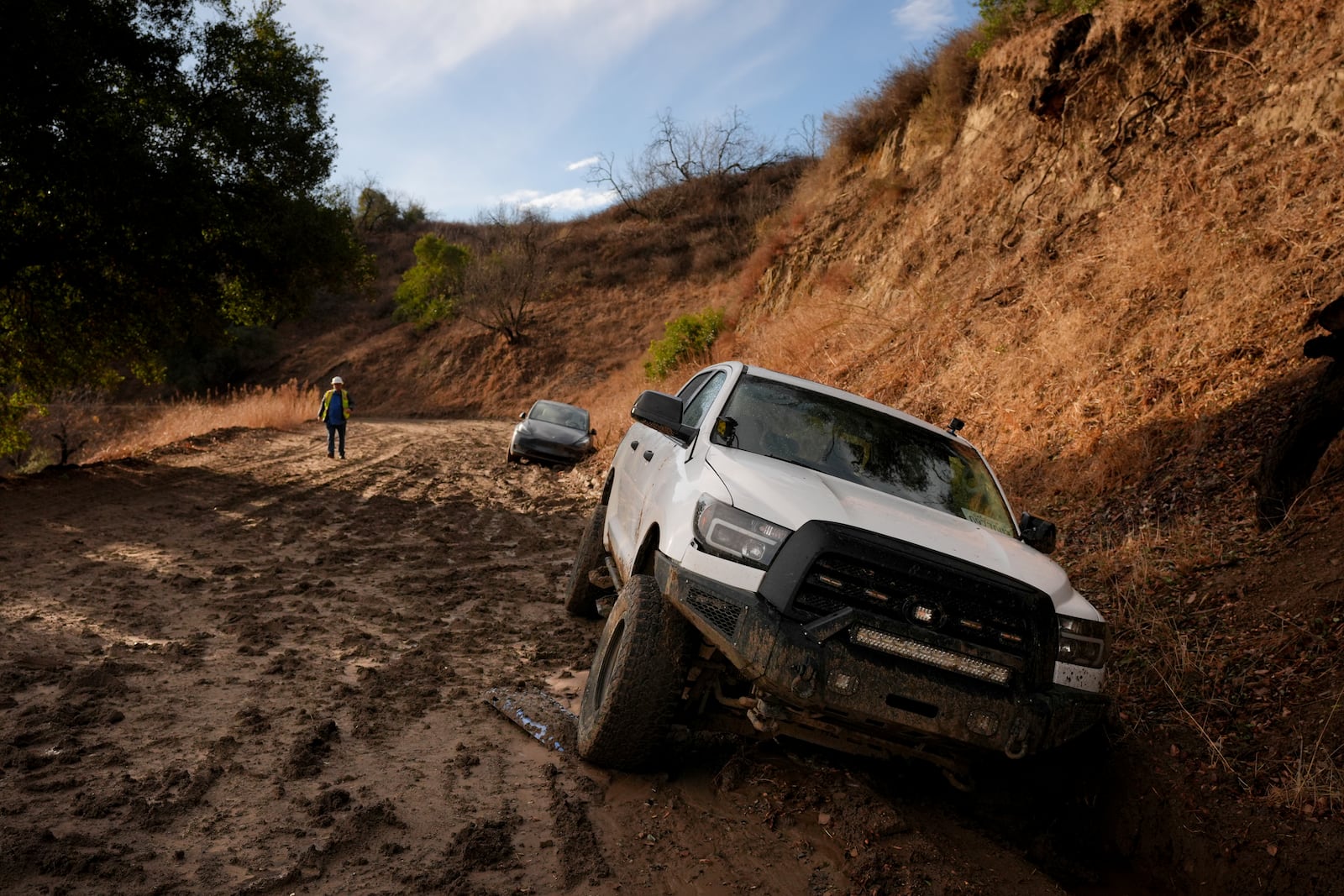 A vehicle is stuck in the mud in an unpaved access road after weekend storms in the Woodland Hills section of Los Angeles, Monday, Jan. 27, 2025. (AP Photo/Jae C. Hong)