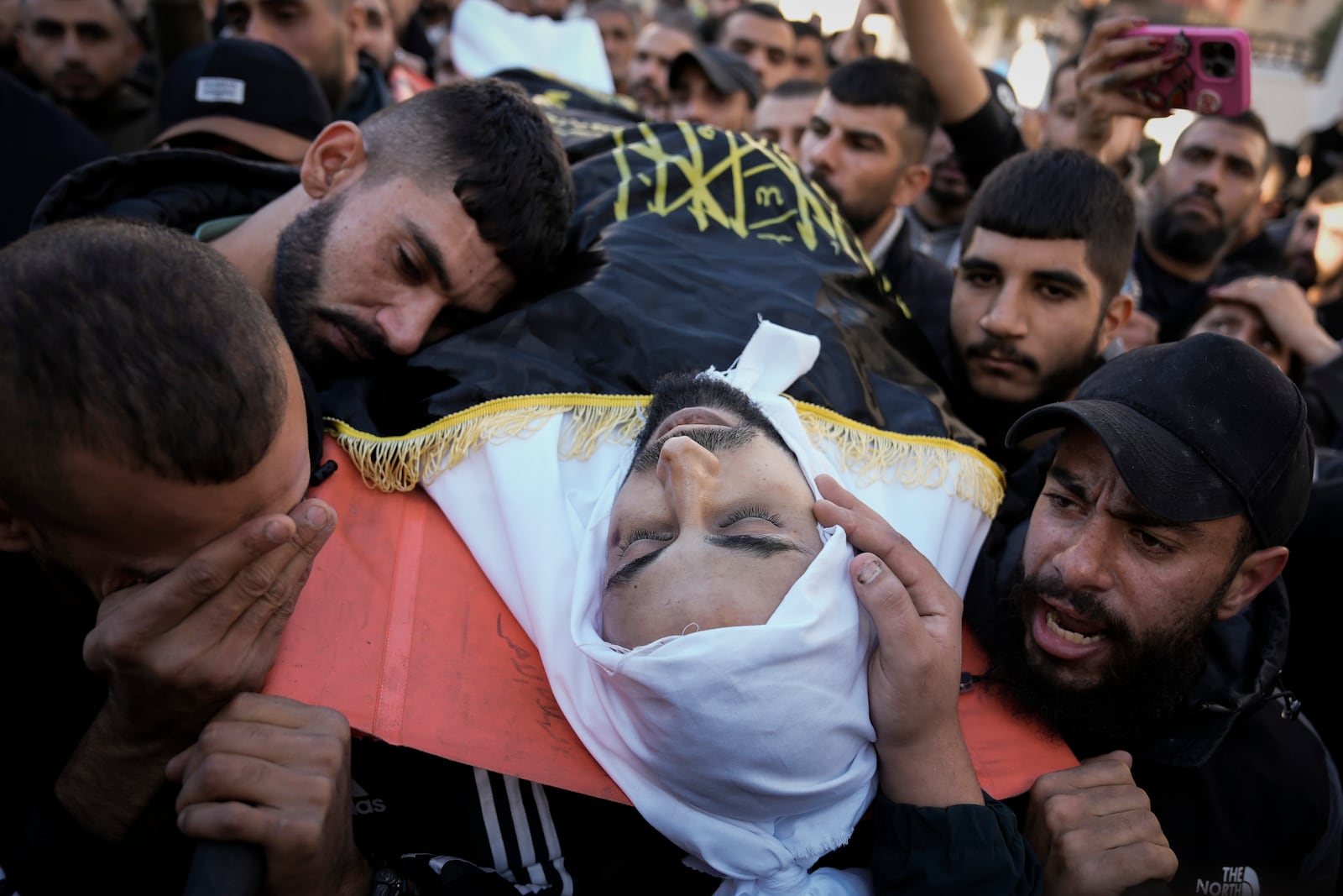 Palestinian mourners gather for the funeral of Islamic Jihad militant Yazid Jaayseh, killed by Palestinian security forces during a raid, carrying his body through the streets of the Jenin refugee camp in the Israeli-occupied West Bank Dec. 17, 2024 (AP Photo/Majdi Mohammed).