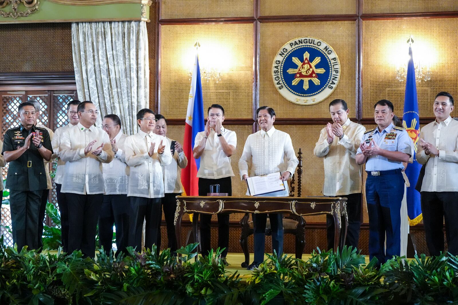 In this photo provided by the Malacanang Presidential Communications Office, Philippine President Ferdinand Marcos Jr., 4th from right, holds a document during the ceremonial signing of the Philippine Maritime Zones and Philippine Archipelagic Sea Lanes Act at the Malacanang presidential palace in Manila, Philippines on Friday, Nov. 8, 2024. (Malacanang Presidential Communications Office via AP)