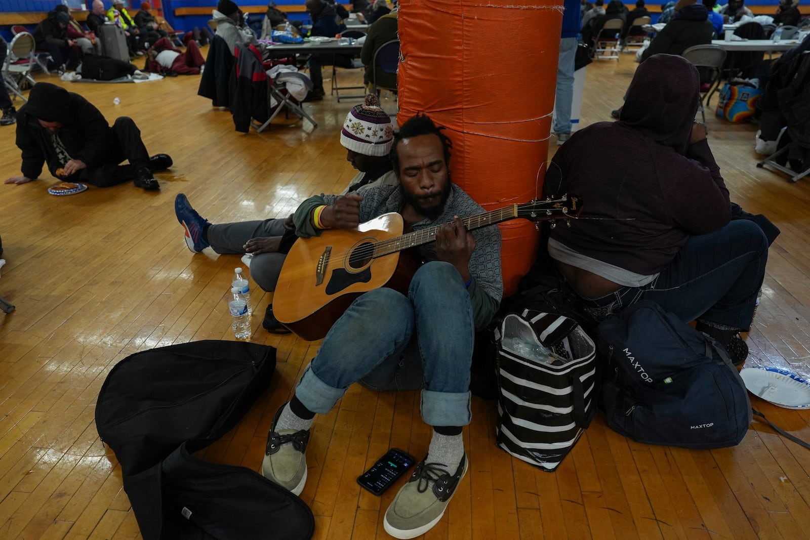 Tirrdell Byrd plays guitar while sheltering from the cold inside a recreation center, Monday, Jan. 6, 2025, in Cincinnati. (AP Photo/Joshua A. Bickel)