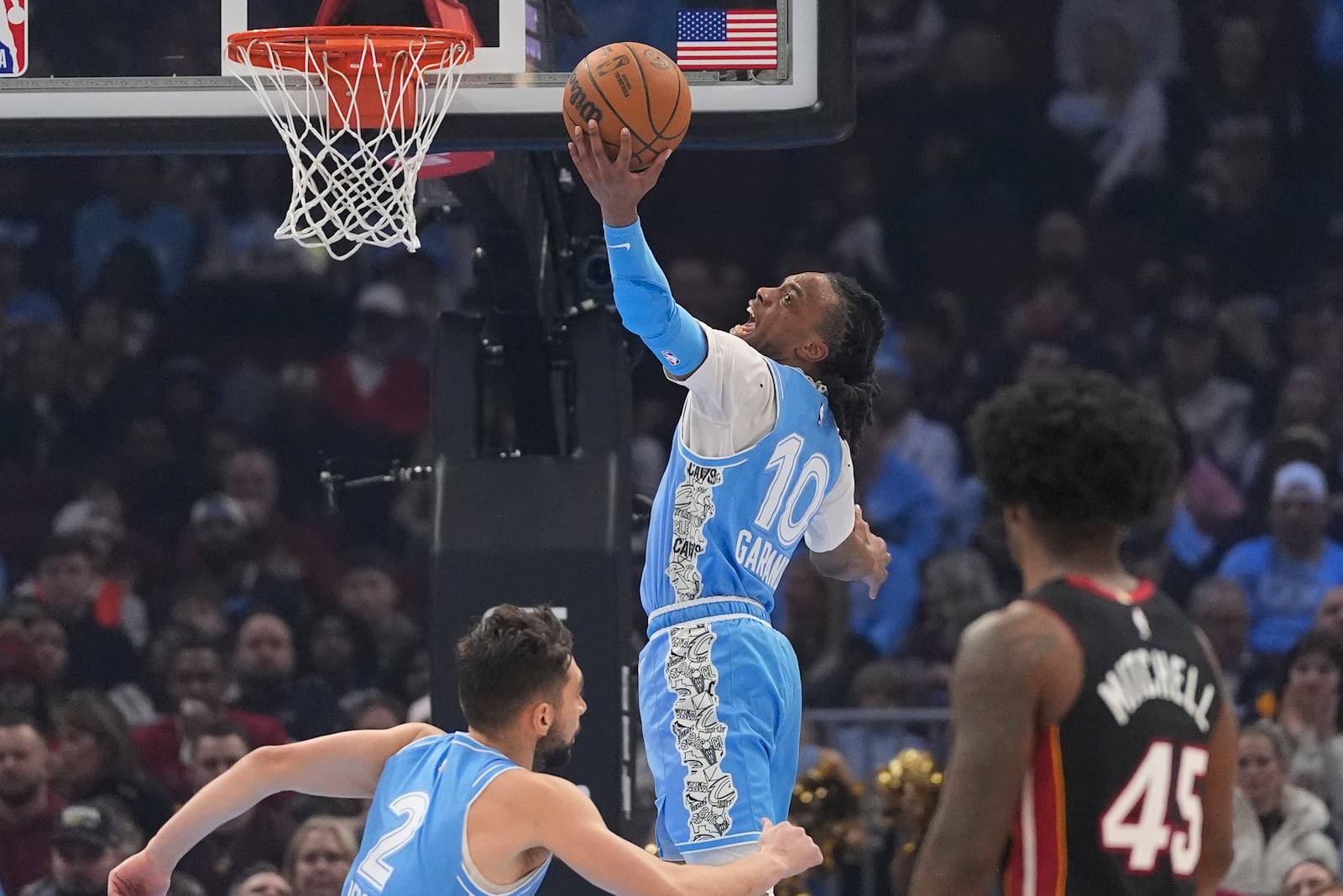 Cleveland Cavaliers guard Darius Garland (10) grabs a rebound in front of teammate Ty Jerome (2) and Miami Heat guard Davion Mitchell (45) in the first half of an NBA basketball game Wednesday, March 5, 2025, in Cleveland. (AP Photo/Sue Ogrocki)