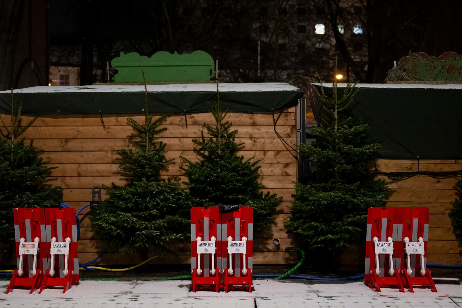 Mobile vehicle barriers sit behind stalls at the Christmas market on Rotkreuzplatz, early Monday, Dec. 23, 2024, in Munich. (Sven Hoppe/dpa via AP)