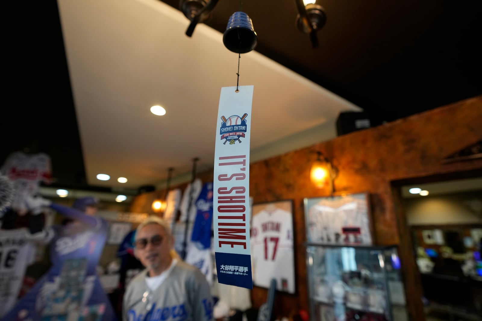 Hironobu Kanno, representative of a private fan club of Shohei Ohtani of the Los Angeles Dodgers, speaks near a Nambu cast iron wind chime, one of famed local products, at his beauty salon in Oshu, northeastern Japan, the hometown of Ohtani, Tuesday, Oct. 29, 2024. (AP Photo/Eugene Hoshiko)