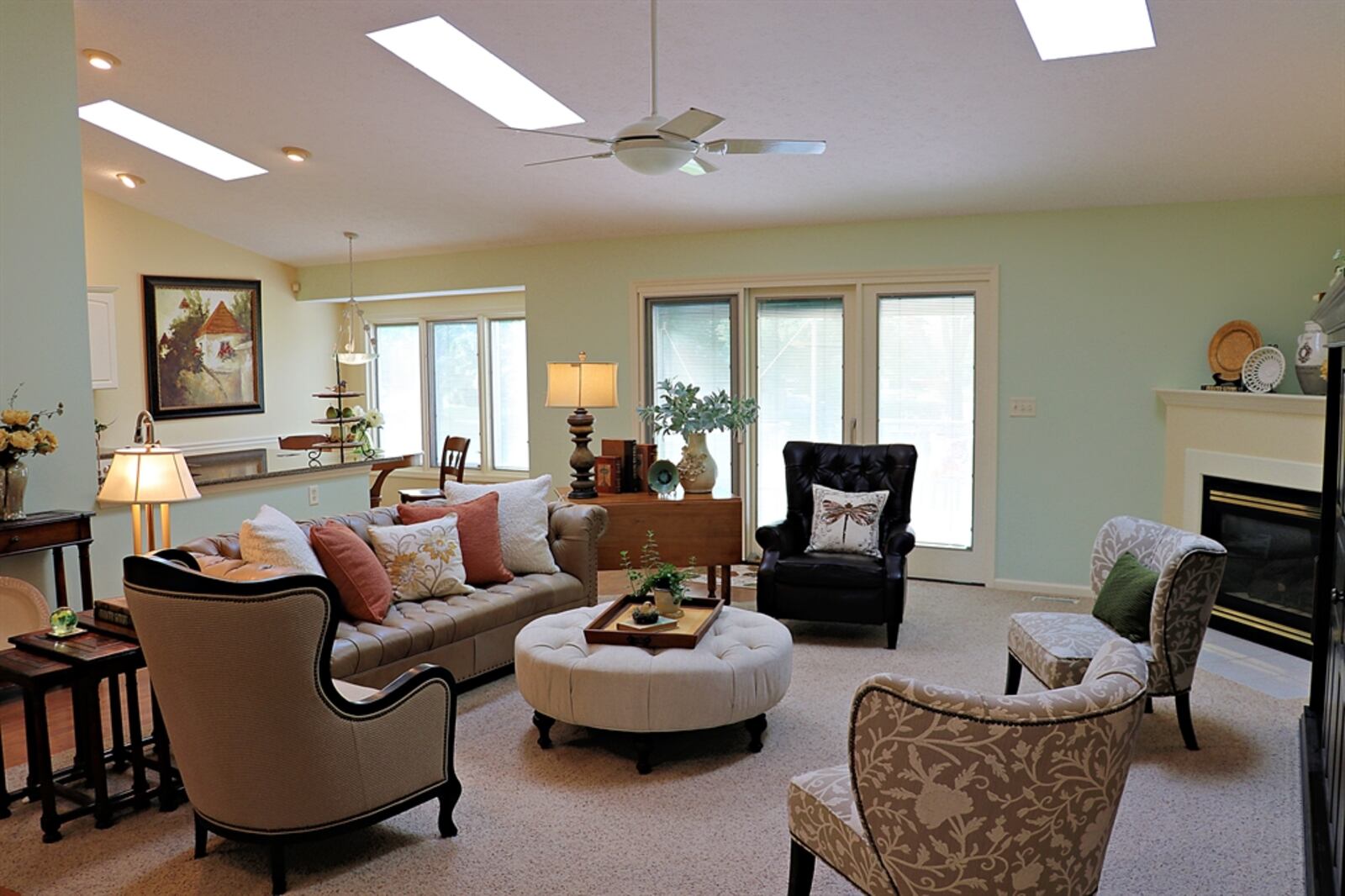 Three skylights and triple windows and doors fill the combined great room and breakfast room with natural light. A gas fireplace with wood-capped mantel and ceramic-tile hearth is tucked into one corner of the great room.