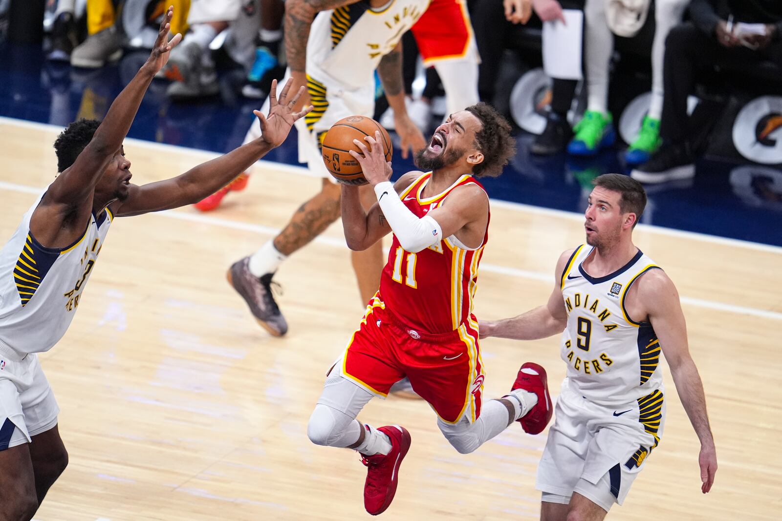 Atlanta Hawks guard Trae Young (11) is fouled as he shoots between Indiana Pacers center Thomas Bryant (3) and guard T.J. McConnell (9) during the second half of an NBA basketball game in Indianapolis, Saturday, Feb. 1, 2025. (AP Photo/Michael Conroy)