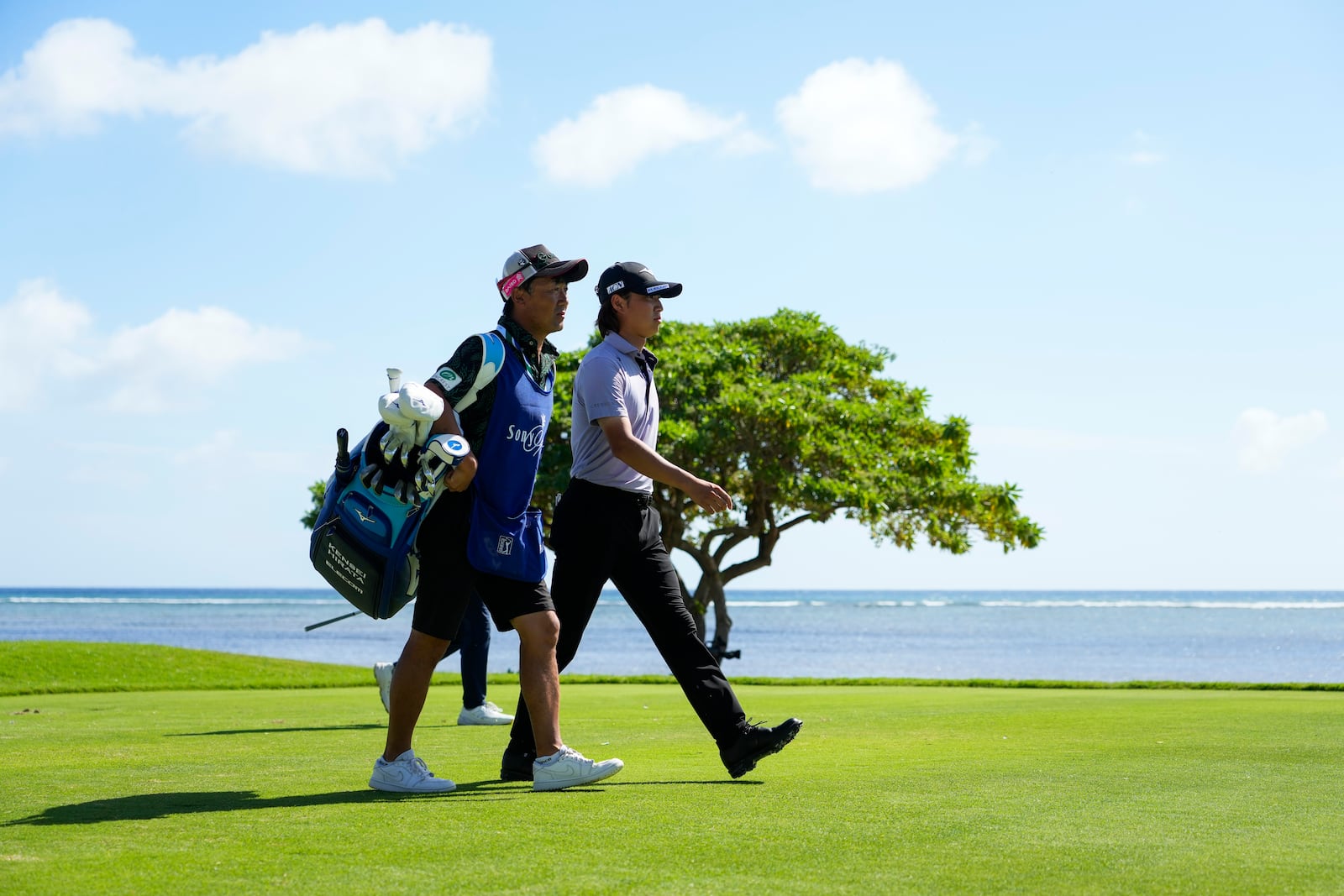 Kensei Hirata, right, of Japan, walks with his caddie on the 17th fairway during the second round of the Sony Open golf event, Friday, Jan. 10, 2025, at Waialae Country Club in Honolulu. (AP Photo/Matt York)