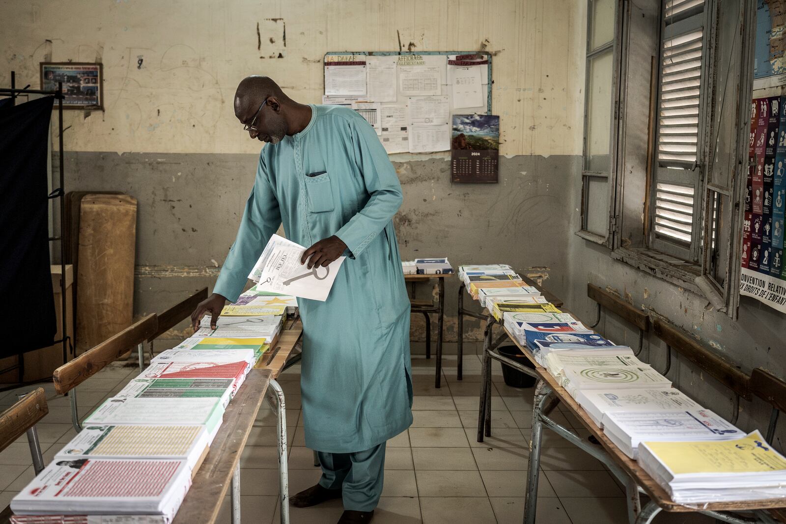 A man collects voting cards, that are set on a table, before casting his vote for legislative elections at a polling station in Dakar, Senegal Sunday, Nov. 17, 2024. (AP Photo/Annika Hammerschlag)