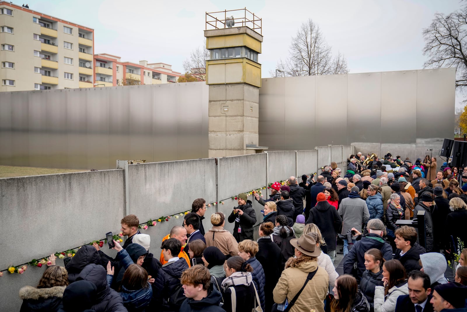 People attend a flower laying ceremony on occasion of the 35th wall anniversary at the grounds of the Berlin Wall Memorial, Berlin, Germany, Saturday, Nov.9, 2024. (AP Photo/Ebrahim Noroozi)