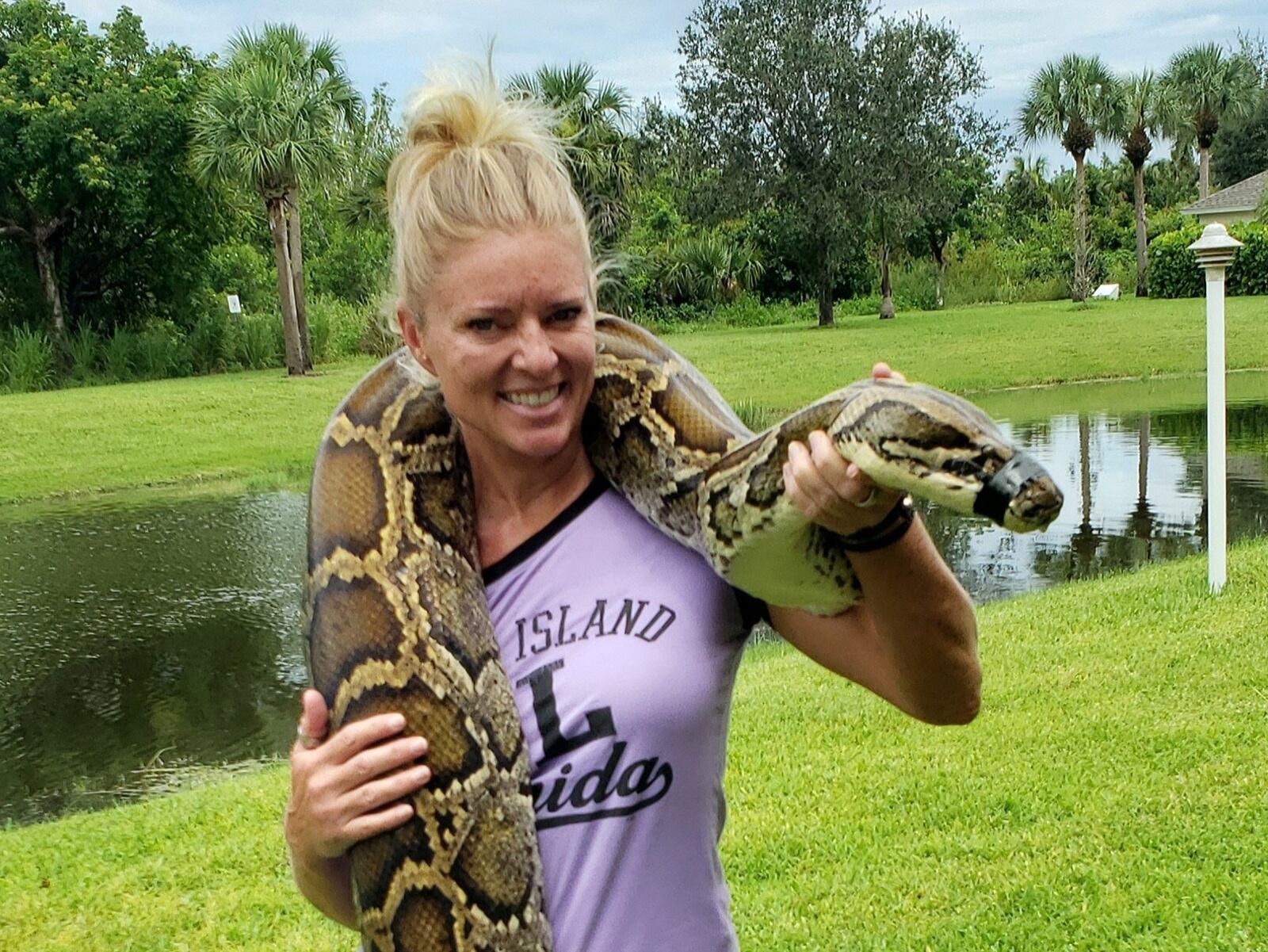 Amy Siewe with the 17-foot-3 inch python she captured last July of the Tamiami Trail in the Everglades. Amy, a former Fairmont High athlete and homecoming queen and University of Toledo tennis player, is now a python hunter contracted by the South Florida Water Management District to help rid the Everglades of the invasive pythons that are killing all the animals and birds they come in contact with and wrecking the ecosystem. CONTRIBUTED