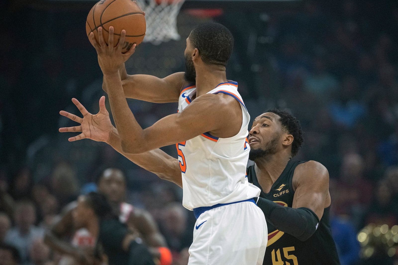 Cleveland Cavaliers' Donovan Mitchell (45) defends against New York Knicks' Mikal Bridge, left, during the first half of an NBA basketball game in Cleveland, Friday, Feb. 21, 2025. (AP Photo/Phil Long)