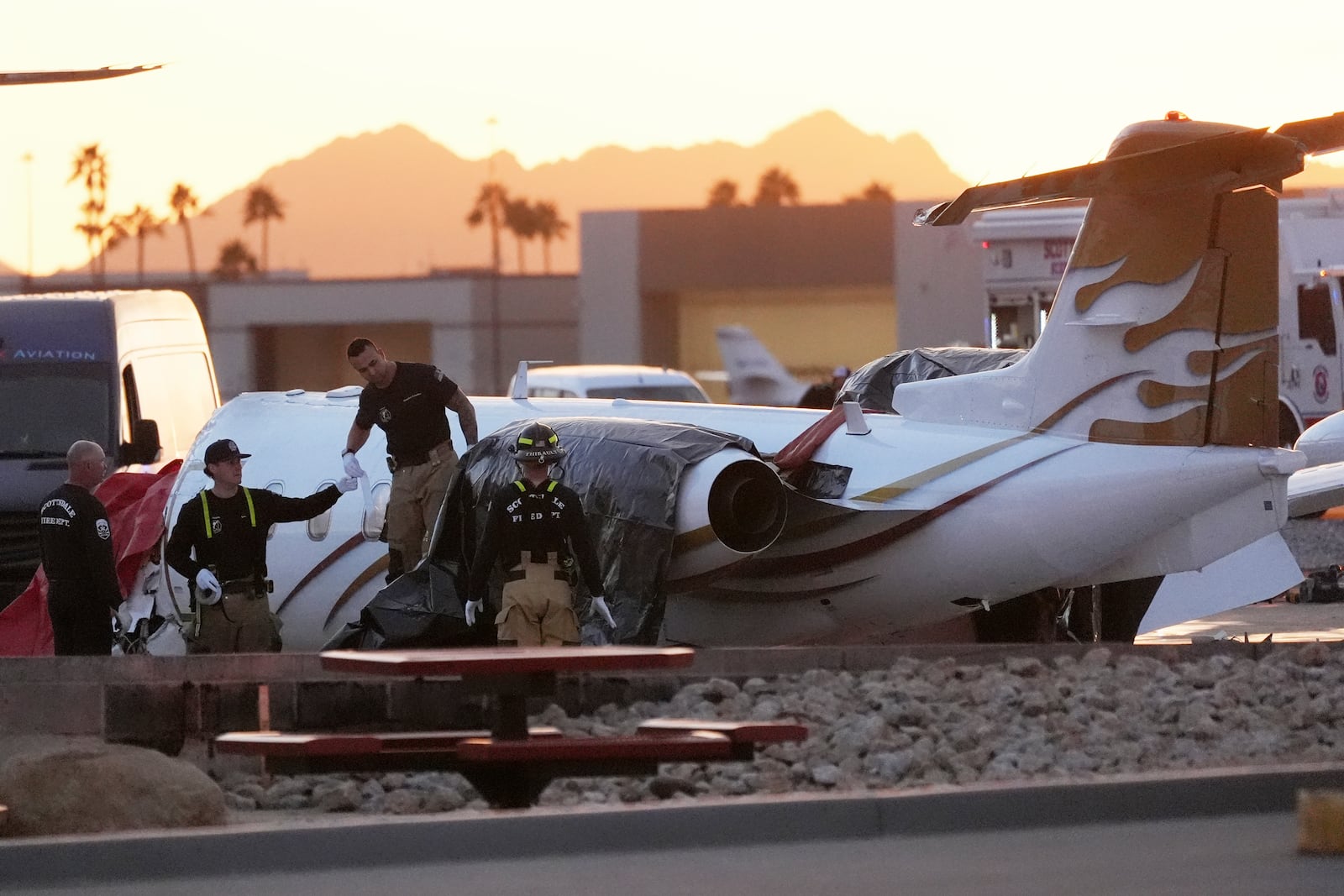 Scottsdale Fire Department firefighters work on a crashed Learjet at Scottsdale Airport after it crashed into another parked plane Monday, Feb. 10, 2025, in Scottsdale, Ariz. (AP Photo/Ross D. Franklin)